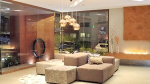 A modern lobby with a sectional sofa, a glass wall, and a fire feature. - Hotel Quo Quality Manizales (Manizales)