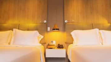 A hotel room with two beds, a nightstand with a lamp, and a wooden panel wall.