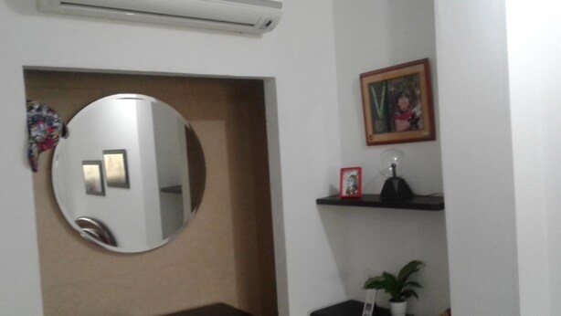 A bathroom with a round mirror, a sink, a shelf with a plant, and a framed picture. - moskafamily (Cartagena)