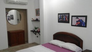 A bedroom with a bed, a wooden headboard, a dresser, a mirror, and two framed pictures on the wall. - moskafamily (Cartagena)