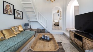 Un salón espacioso con una escalera, un televisor de pantalla plana grande y un sofá.