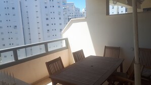 Un balcone con tavolo e sedie, con vista su una fila di palazzi bianchi.