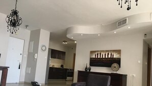 Un soggiorno moderno con un tavolino in vetro, una poltrona in pelle scura e un lampadario.