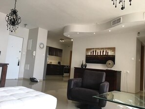 Un salon moderne avec une table basse en verre, un fauteuil en cuir foncé et un lustre.