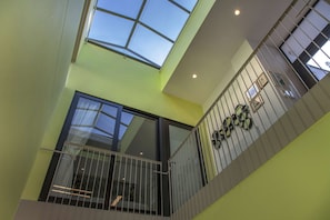 A multi-level interior with a skylight, a balcony with a railing, and a wall-mounted clock.