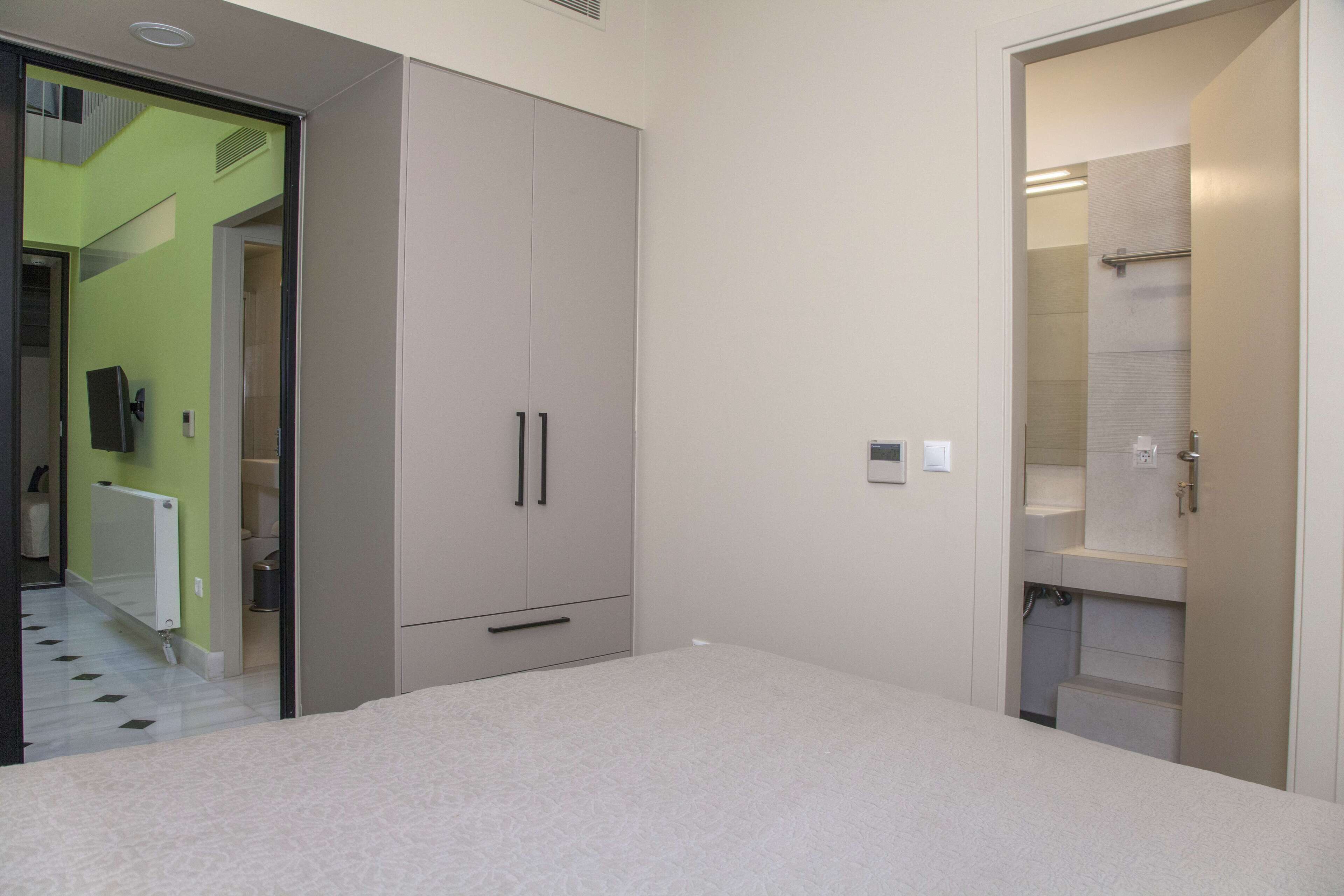 A bedroom with a bed, a wardrobe, and a bathroom with a shower.