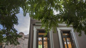 A building with a traditional architectural style, featuring a stone facade and arched windows. - Tripodon Plaka in the shade of Acropolis by GHH (Athens)