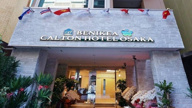 Una entrada de hotel moderna con un cartel para Benikea Calton Hotel El Osaka.