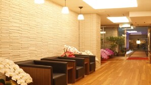 Una zona de recepción con piso de madera, pared de piedra y asientos decorados con flores blancas.