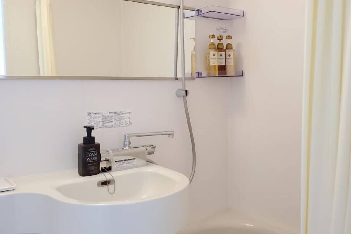 Ein Badezimmer mit einem weißen Waschbecken, einem Spiegel und einem Ablagebereich für Toilettenartikel.