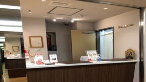 Un mostrador de recepción con detalles de madera, un certificado enmarcado en la pared y un cartel de Benikawa Japan.
