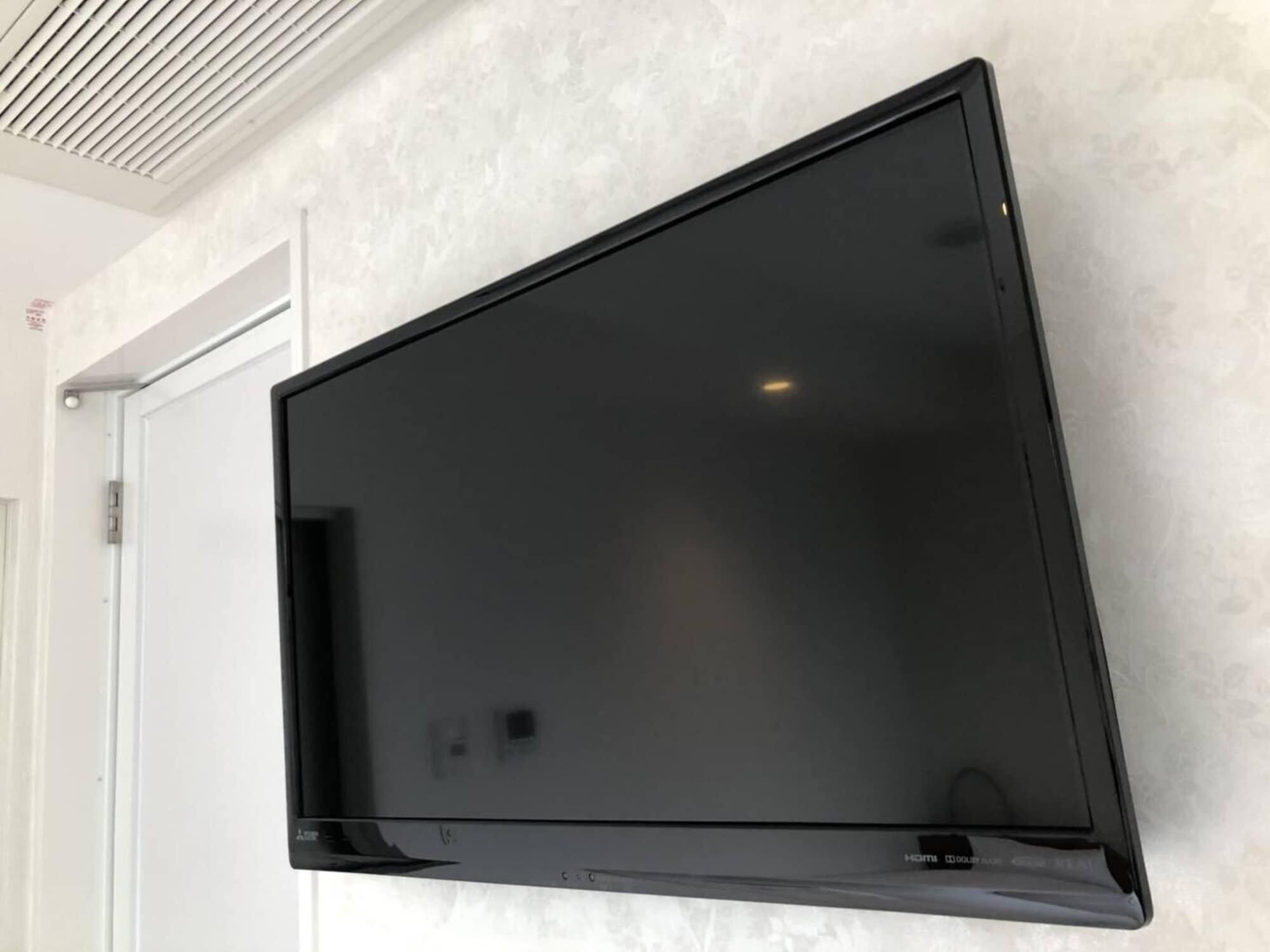 A flat-screen TV mounted on a textured wall.