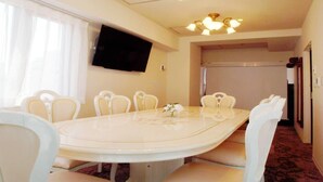 Comedor con una mesa redonda, sillas blancas, televisor de pantalla plana y lámpara en el techo.