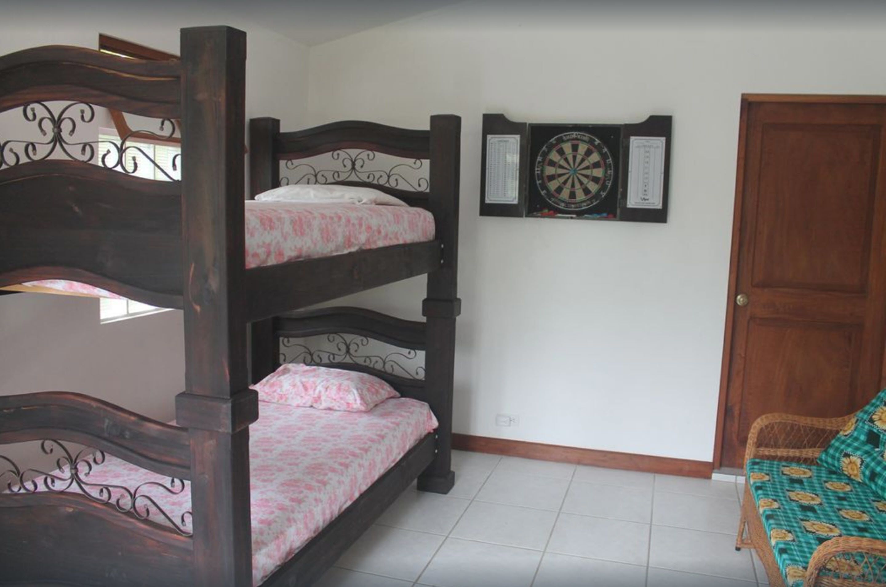Une chambre avec un lit superposé, un jeu de fléchettes et un fauteuil en osier.