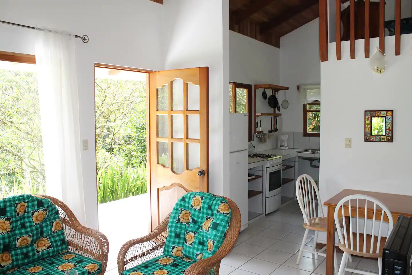 Une pièce avec des chaises en osier, une table à manger et un coin cuisine équipé d’une cuisinière et d’un évier.