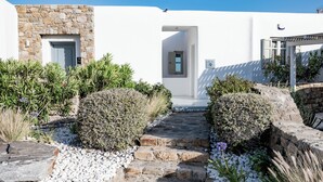 Un sendero de piedra que conduce a un edificio blanco con una entrada de piedra y una puerta.