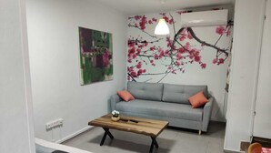 Uma sala de estar com um sofá cinza, uma mesa de centro de madeira e um quadro na parede.