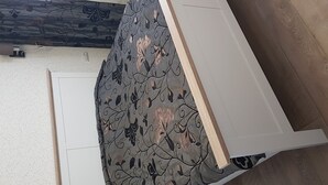 Un lit avec une couvre-lit à motifs floraux, une tête de lit blanche et un plancher en bois.