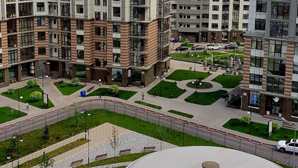 Un immeuble résidentiel de grande hauteur, doté de nombreux étages, d’une cour intérieure et d’un bâtiment aux lignes courbes en premier plan.
