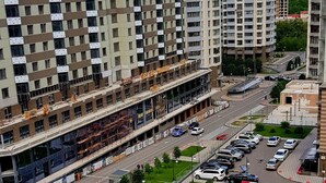 Un immeuble résidentiel de grande hauteur doté de nombreux balcons, d’un espace de stationnement et d’un terrain de sport.
