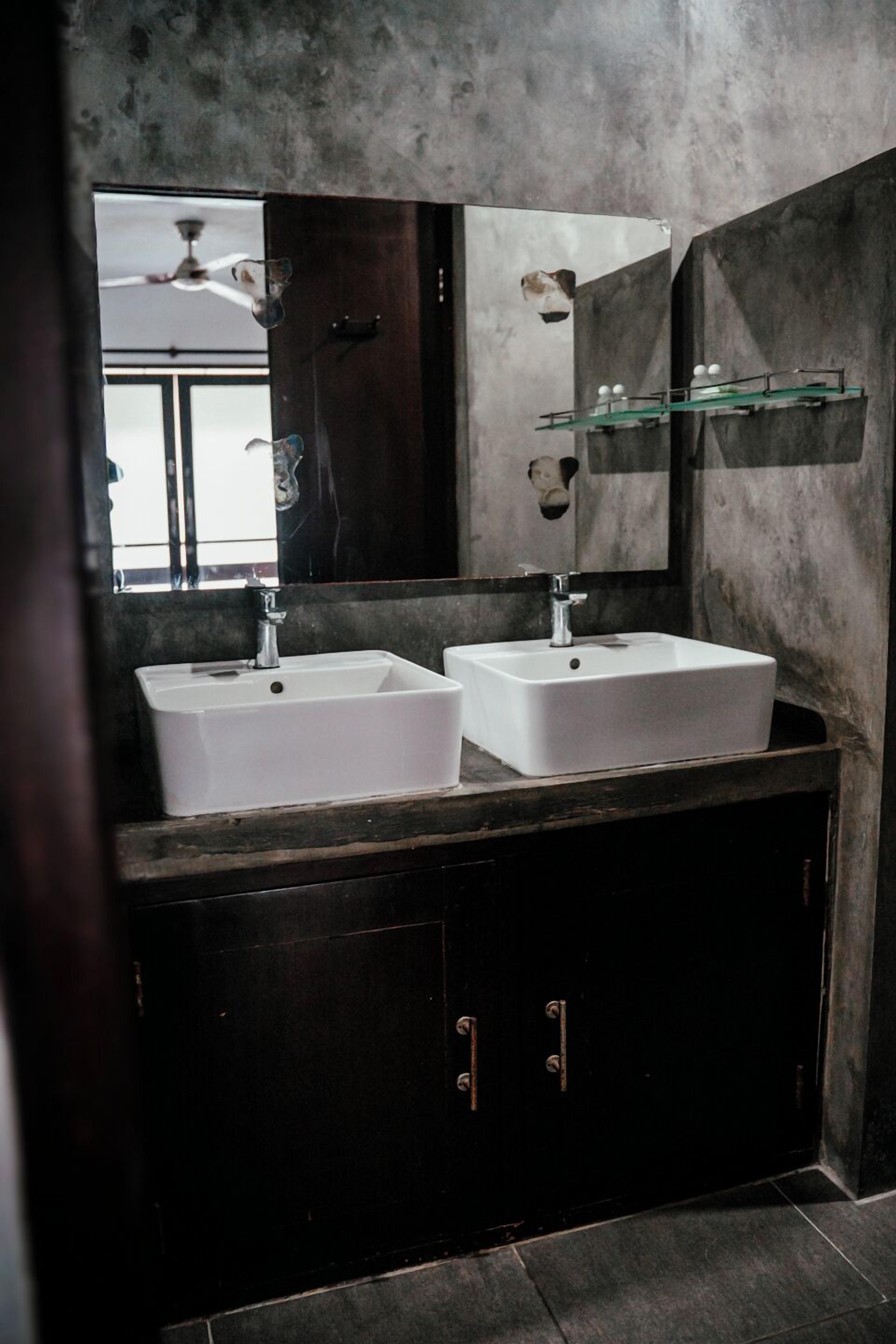 Un baño con dos lavamanos blancos, muebles de madera oscura y un espejo grande.