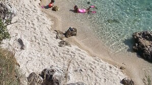 A beach with clear water, rocks, and people.