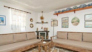 A living room with a stone-patterned floor, a wooden sofa, a small wooden table, and a fireplace with a mantle.
