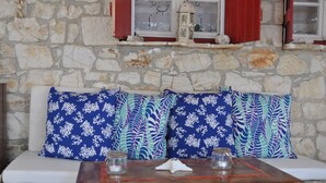 A stone wall with a white bench and patterned cushions.