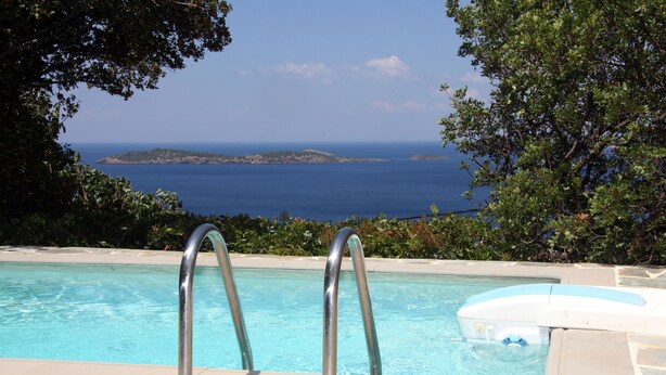 Una piscina con barandales metálicos, un jacuzzi y vistas al mar y a islas distantes.