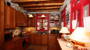 Una cocina rústica con armarios de madera, una pared de piedra y una puerta roja.