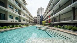 A swimming pool with clear water, surrounded by a tiled deck and lush greenery. - College Haus (Bangkok)