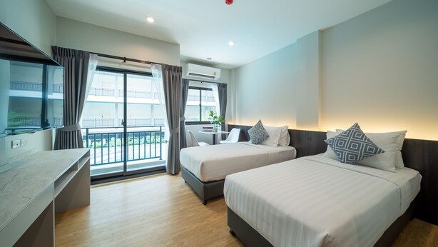 A modern hotel room with two beds, a desk, and a balcony with a view. - College Haus (Bangkok)