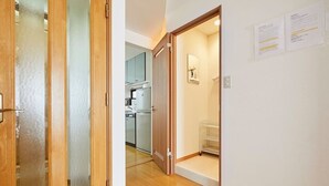 A hallway with wooden doors, a kitchen area in the background, and a white wall with some papers. - Senior villa 4BR, Shinjuku Okubo (東京)