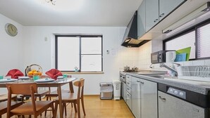 A modern kitchen with a dining area, featuring stainless steel appliances, a window, and a clock on the wall. - Senior villa 4BR, Shinjuku Okubo (東京)