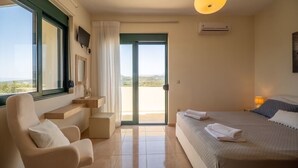 A bedroom with a bed, a chair, a desk, and a view through a glass door. - Holiday villa with private pool (Ξηροκάμπι)