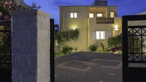 Un bâtiment à deux étages avec une allée pavée et une entrée fermée par un portail.
