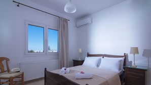 Une chambre bien rangée, avec un lit, une chaise, une table de chevet et une fenêtre avec des rideaux.