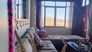 Uma sala de estar com sofá, mesa de centro e vista para o exterior.