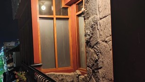 Uma varanda com parede de pedra, porta de madeira e vasos de plantas.