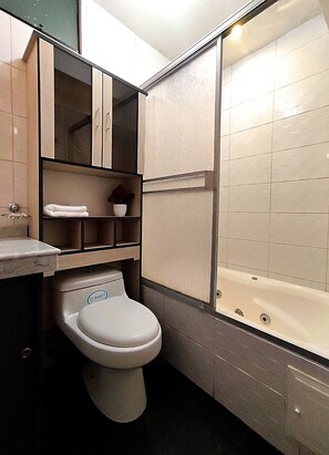 A modern bathroom with a toilet, a sink, a vanity with a mirror, and a shower area. - El Balcón del Sol (Cusco)