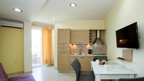 A modern kitchen with a dining area, a flat-screen TV, and a sofa. - Waterfront apartment 4 (Κίσσαμος)