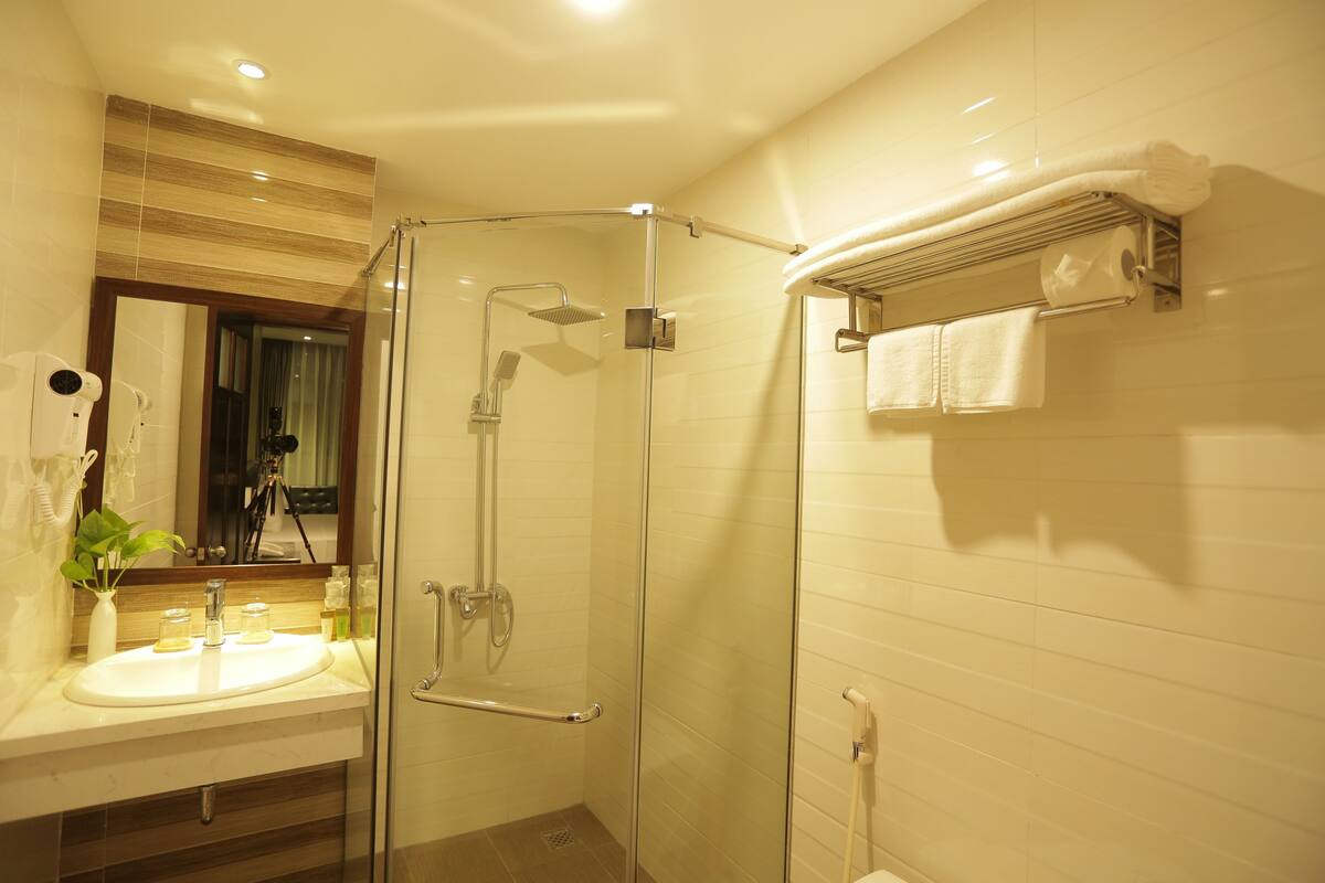 A modern bathroom with a glass-enclosed shower, a sink with a mirror, and a towel rack.