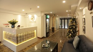 Zona de recepción de un hotel, con mostrador de recepción, un árbol de Navidad y un sofá.