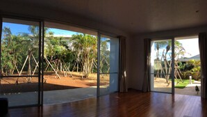 Amplia habitación con grandes puertas correderas de vidrio que dan a un espacio exterior con palmeras y una vista despejada del cielo.