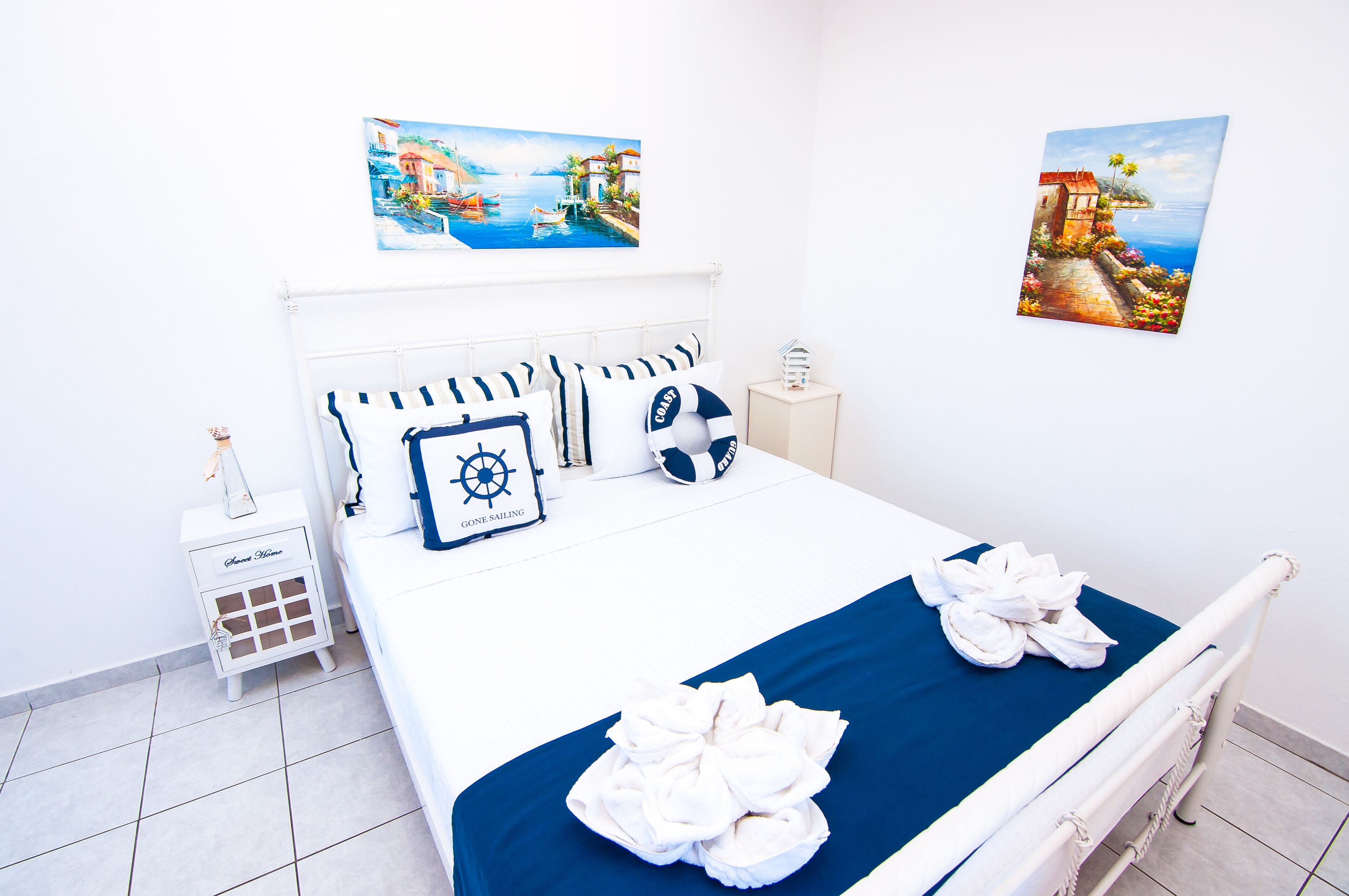 Une chambre d’hôtel avec un lit, des oreillers, une table de chevet et deux tableaux au mur.