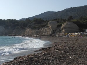 A beach with rocky terrain and a few people. - Apartment "Grace" with 2 spaces, at the foothills of Filerimos, Ialysos - Rhodes (Ιαλυσός)