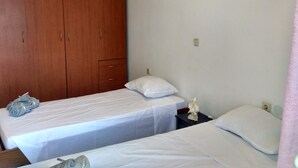 A room with two single beds, a wooden wardrobe, and a wall-mounted sign. - Apartment "Grace" with 2 spaces, at the foothills of Filerimos, Ialysos - Rhodes (Ιαλυσός)