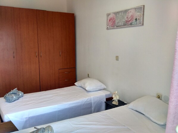 A room with two single beds, a wooden wardrobe, and a wall-mounted sign.