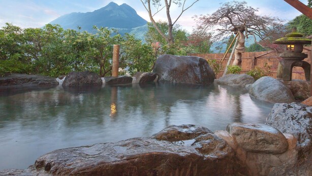 A tranquil garden with a pond, large rocks, and a wooden structure. - Yufuin Sanso Waremokou (Yufu)