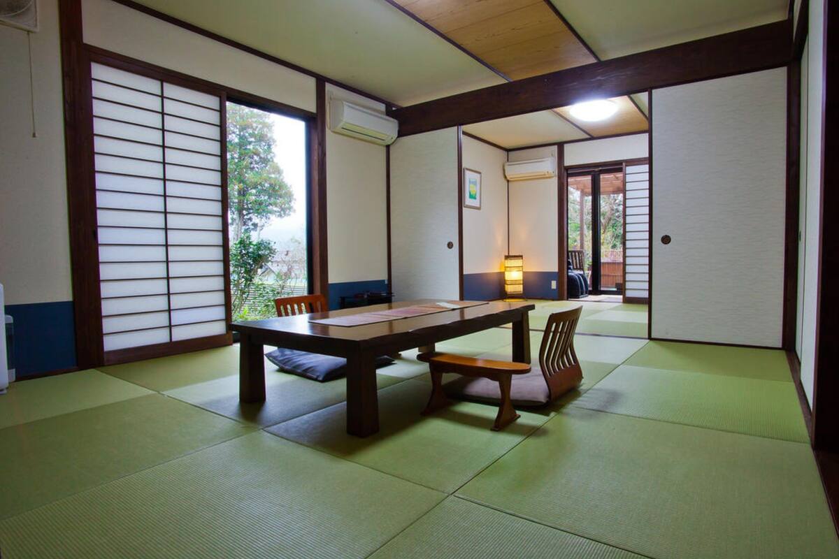 A traditional Japanese room with tatami flooring, a low wooden table, and sliding doors.